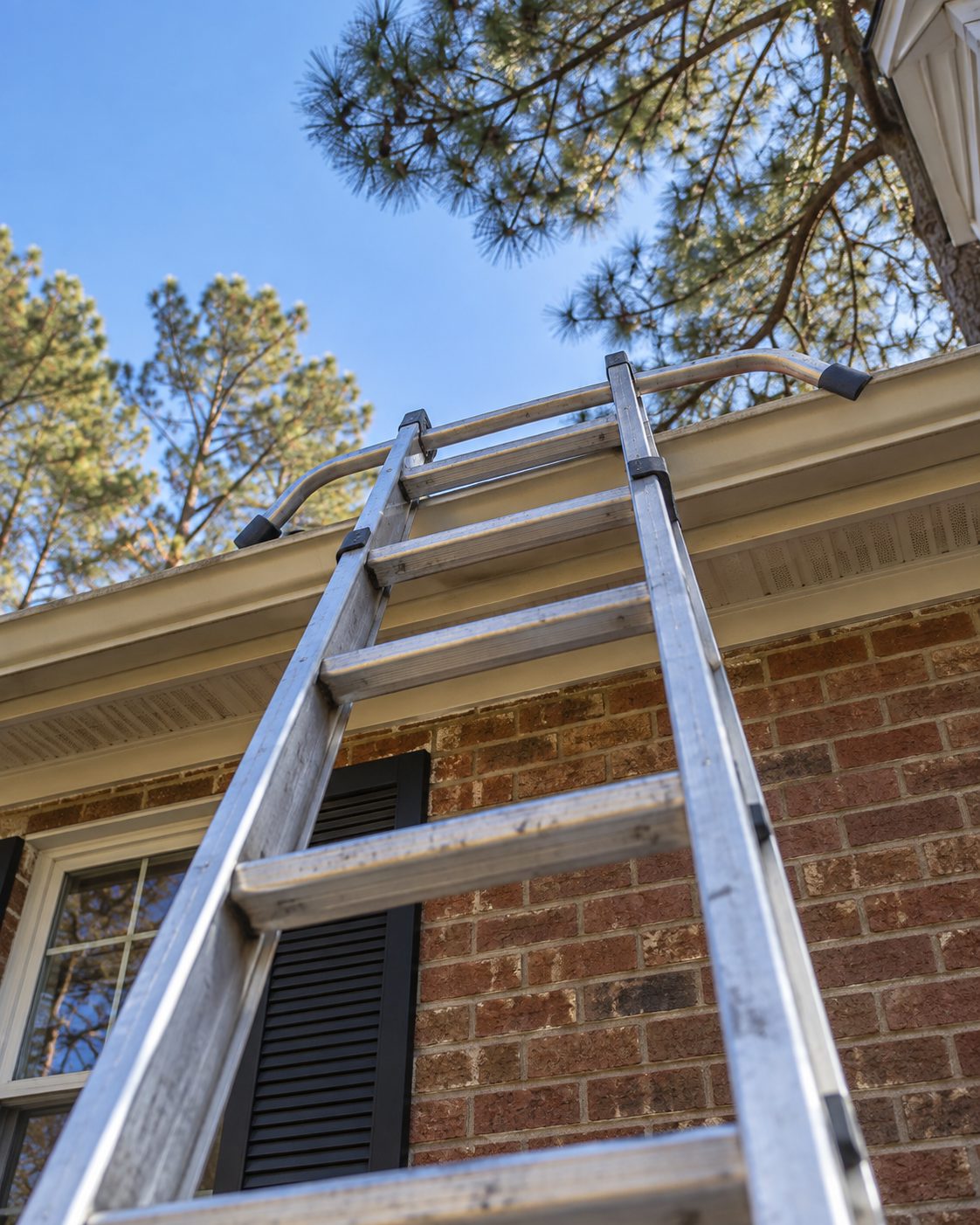 Extension ladder leaning against the eave of a brick house